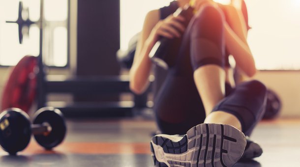 persona sentada en el suelo de un gimnasio después de hacer ejercicio